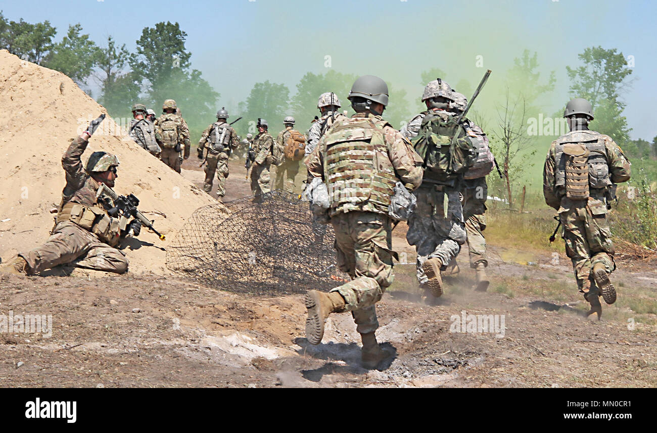 Infantrymen from Bravo Company, 1st Battalion, 158th Infantry Regiment, Arizona National Guard assault through an objective after popping smoke during a Northern Strike 17 field training exercise at Camp Grayling Joint Maneuver Training Center, Aug. 1, 2017. The newly accredited NS 17 demonstrates the Michigan National Guard’s ability to provide accessible, readiness-building opportunities for military units from all service branches to achieve and sustain proficiency in conducting mission command, air, sea, and ground maneuver integration, together with the synchronization of fires in a joint Stock Photo