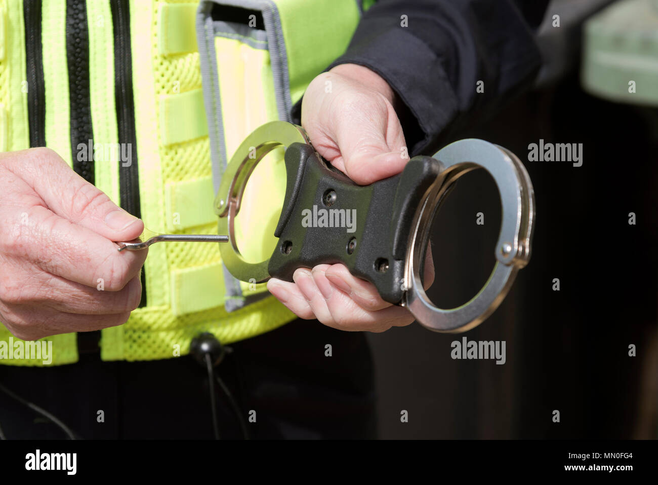 Close up of police officer holding the key to a pair of handcuffs Stock