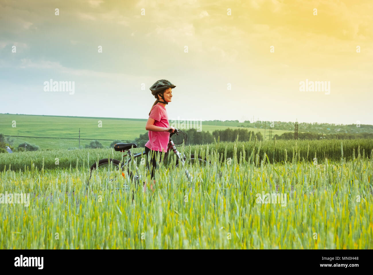 girl on a bicycle in summer rural landscape Stock Photo