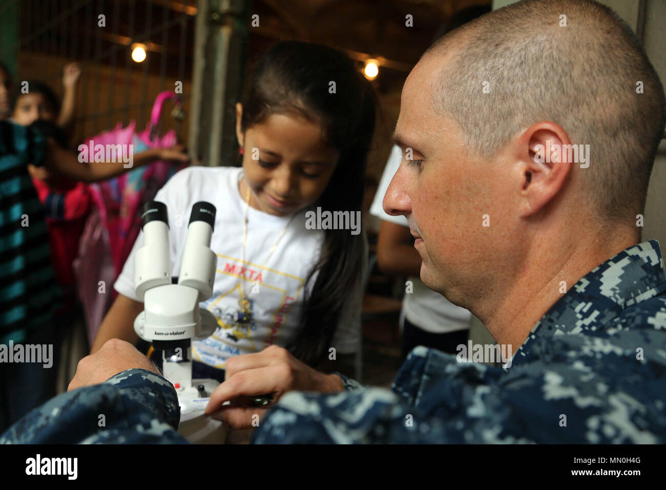 170804-A-QE286-401 TARROS, Honduras (Aug. 4, 2017) U.S. Navy Lt. Cmdr. Ian Sutherland, technical director for the Navy Entomology Center of Excellence, helps Honduran elementary school students view insects through a microscope, during an entomology class at Escuela Rural Mixta Luz Infantil, as part of a Southern Partnership Station 17 community relations (COMREL) project. SPS-EPF 17 is a U.S. Navy deployment, executed by U.S. Naval Forces Southern Command/U.S. 4th Fleet, focused on subject matter expert exchanges with partner nation militaries and security forces in Central and South America. Stock Photo