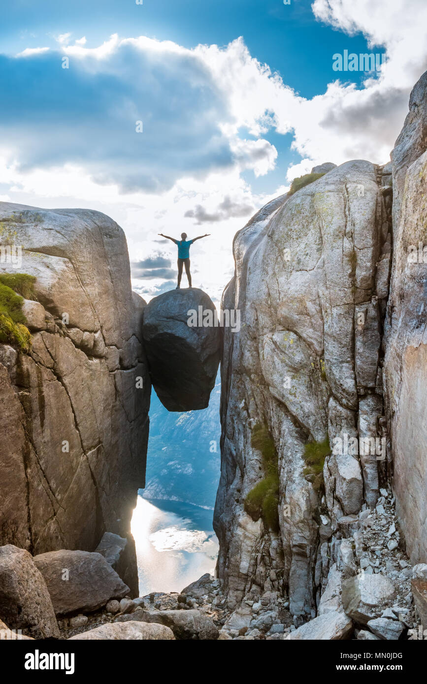 Woman on Kjeragbolten Travel in Norway Kjerag mountains, extreme vacations, adventure, tourist, happy emotions, success concept Stock Photo