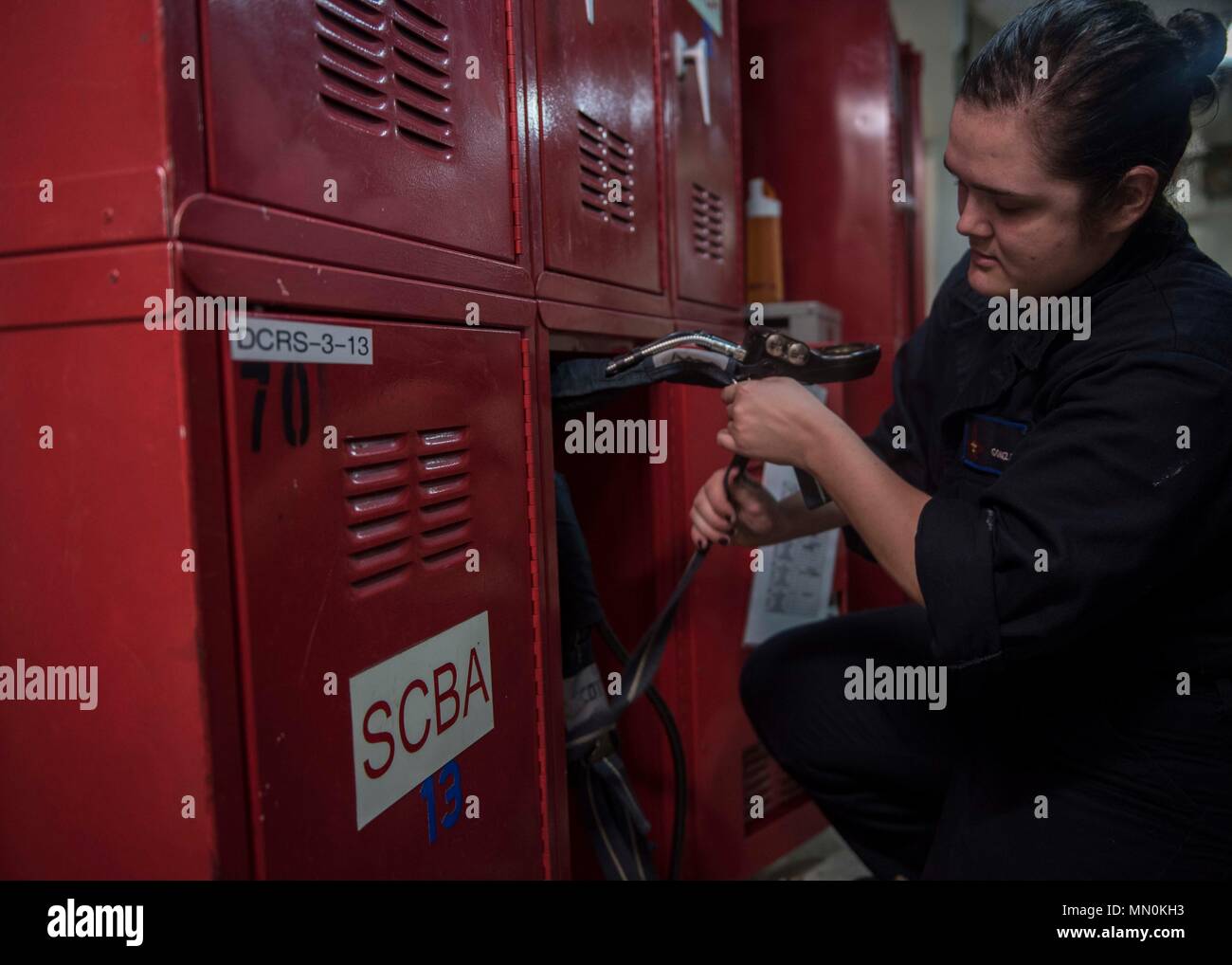 170802-N-AJ467-009 ATLANTIC OCEAN (Aug. 2, 2017) Damage Controlman Fireman Andrea Gonzales stows a self-contained breathing apparatus bottle back in its locker after maintenance aboard the aircraft carrier USS George H.W. Bush (CVN 77). The ship and its carrier strike group are conducting naval operations in the U.S. 6th Fleet area of operations in support of U.S. national security interests in Europe and Africa. (U.S. Navy photo by Mass Communication Specialist Seaman Darien Weigel/Released) Stock Photo