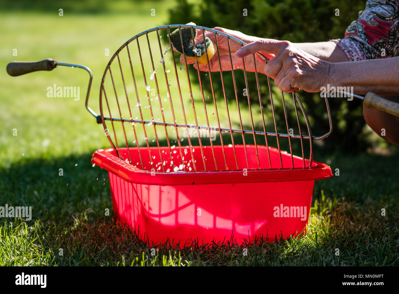Woman cleaning up the barbecue grill Stock Photo