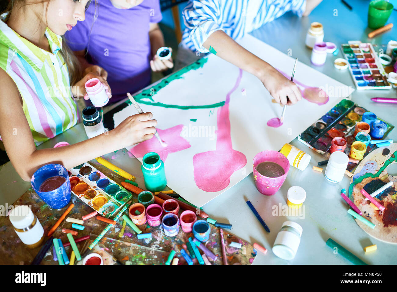 Group of unrecognizable children painting pictures with watercolors ...