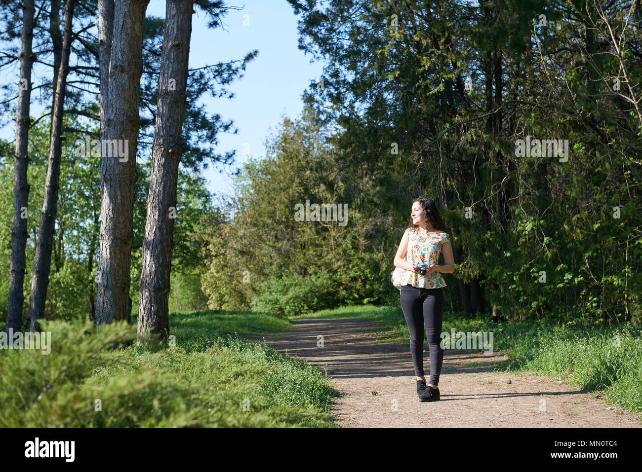 young girl walking in spring forest with camera and taking pictures ...