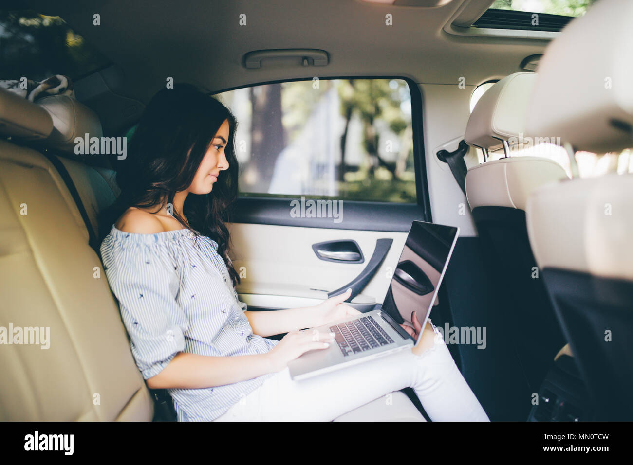 Business woman sitting with laptop and working on backseat of car Stock Photo