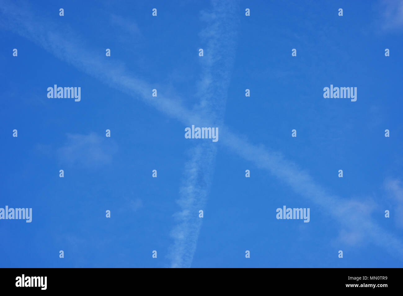 Plane traces in x shape with  little veil clouds Stock Photo