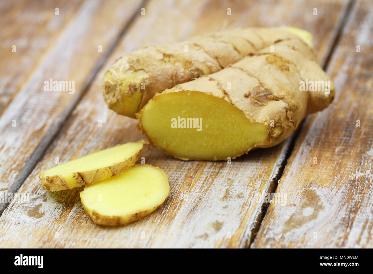 Slices of fresh ginger on rustic wooden surface Stock Photo