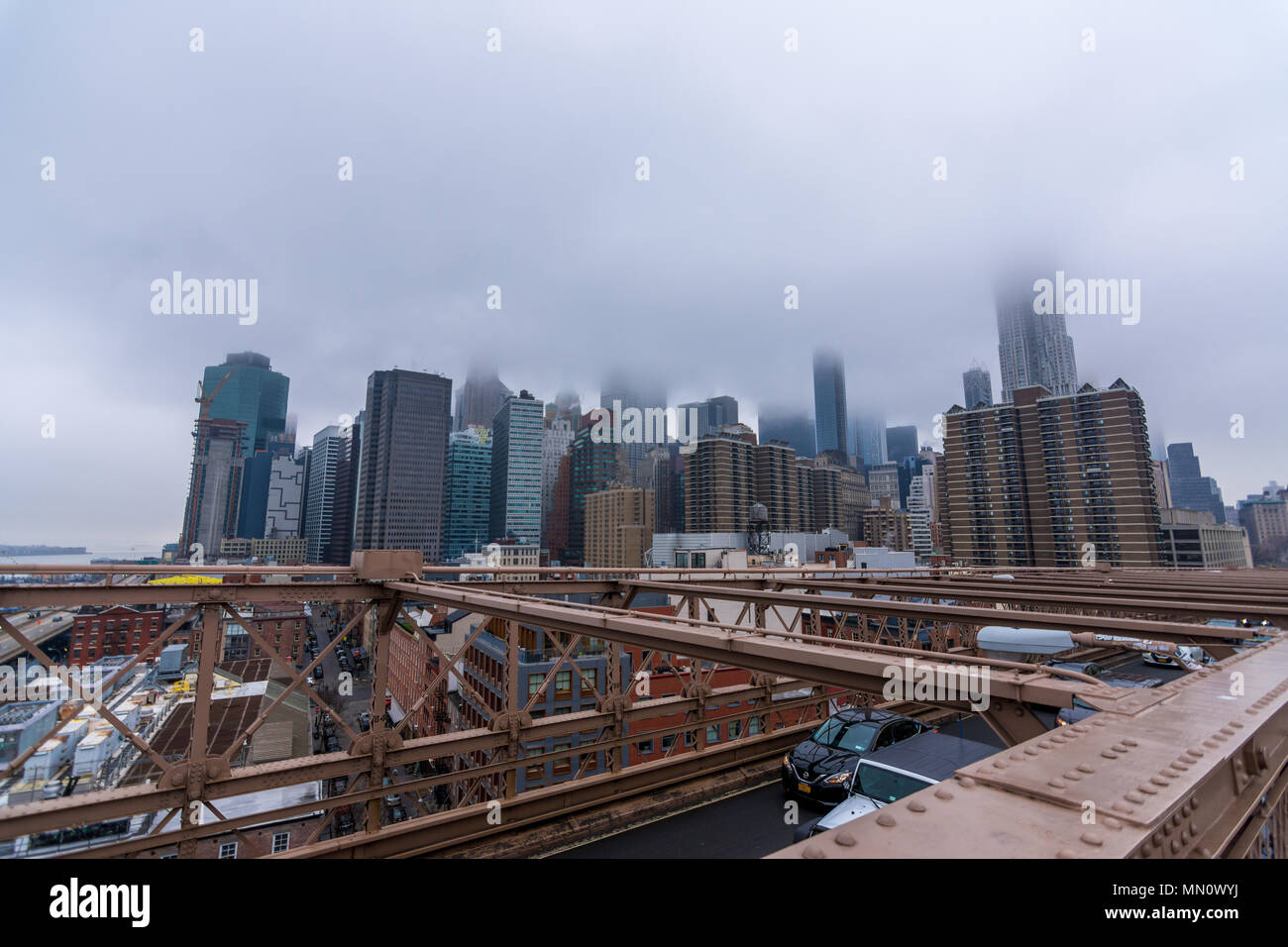 New York, US - March 29, 2018: Downtown Manhattan with buildings obsucured under heavy fog as seen from Brooklyn bridge Stock Photo