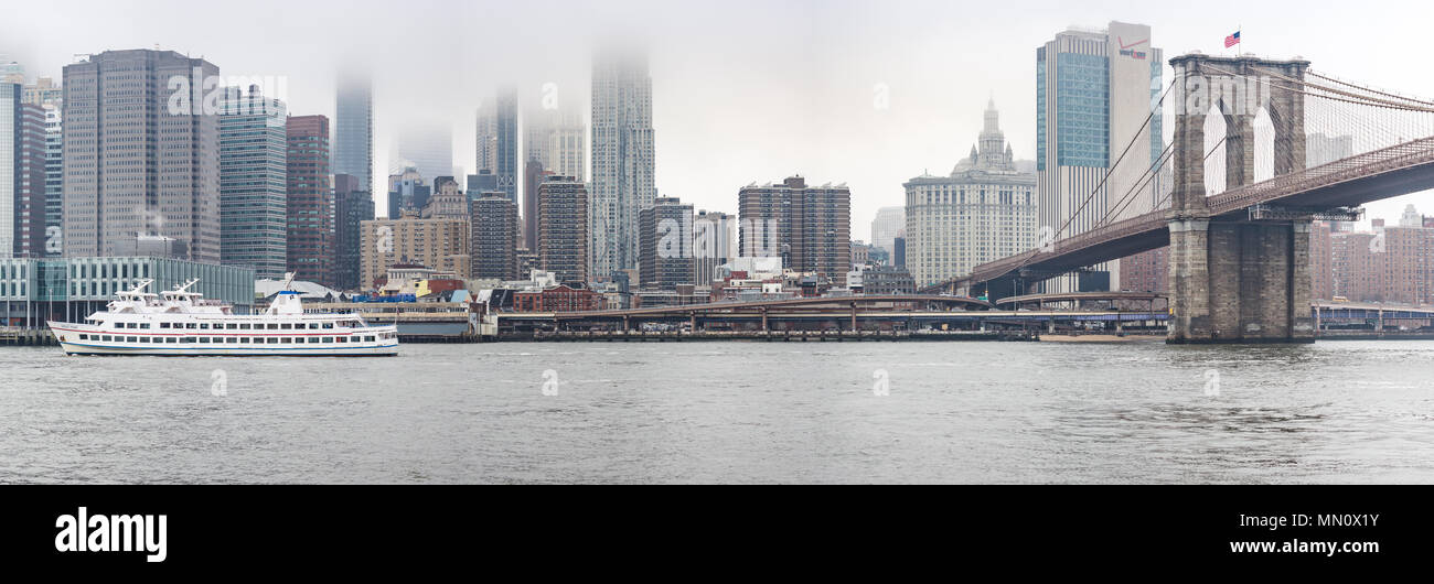 New York, US - March 29, 2018:  Brooklyn bridge and downtown Manhattan on a foggy day in New York as seen from a promenade in Brooklyn Stock Photo