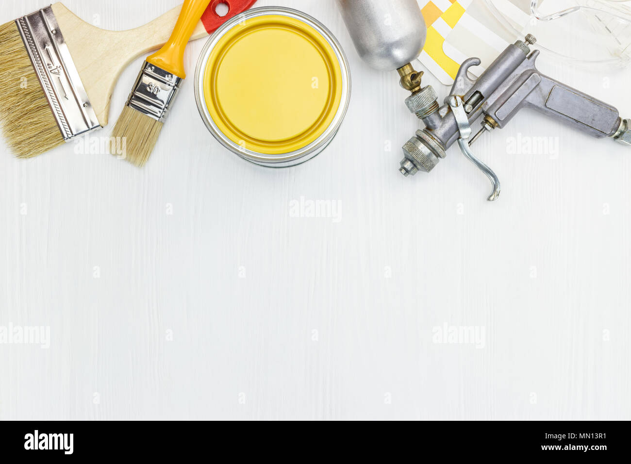 house renovation equipment. brushes, paint spray gun, can, color samples on white wooden background Stock Photo