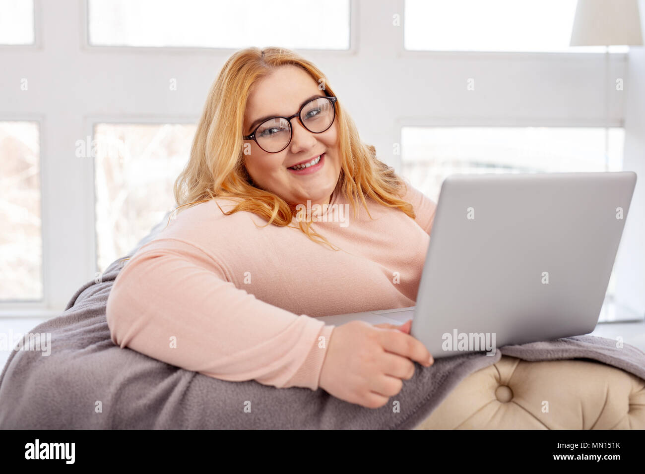 Delighted fat woman sitting with her laptop Stock Photo