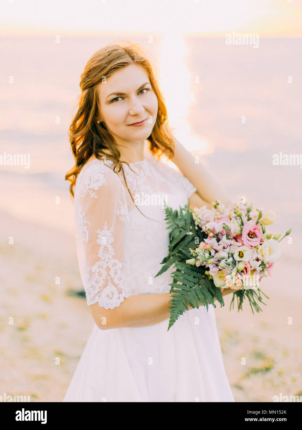 The close-up portrait of the bride holding the bouquet. The sunset composition. Stock Photo
