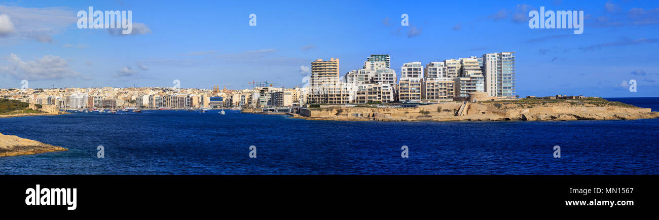 Malta, Valletta. Sliema town with multistorey waterfront buildings, blue sea and blue sky with few clouds background. Panoramic view, banner. Stock Photo