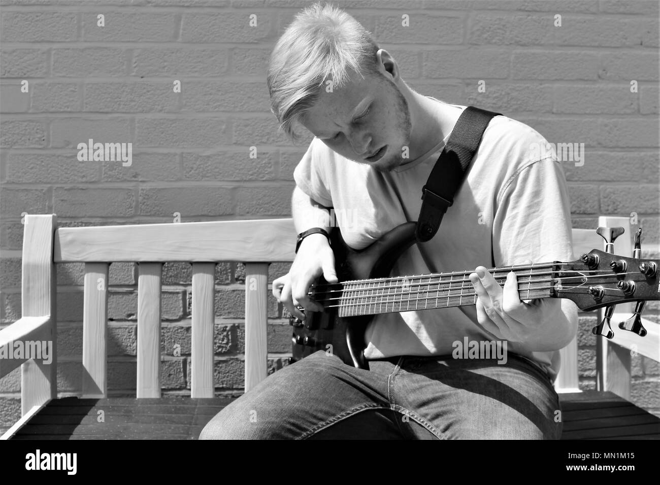 Seventeen year old teenage Caucasian male playing bass guitar outdoors. Stock Photo