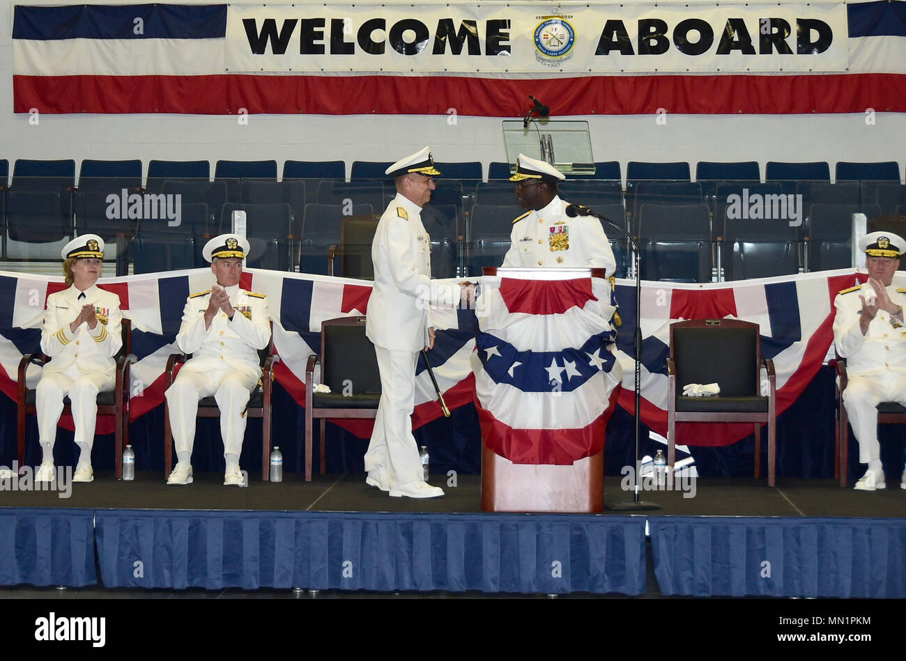 GREAT LAKES, Ill., (August 9, 2017) -- Rear Adm. Stephen C. Evans (right) is congratulated by Vice Adm. Robert P. Burke, Chief of Naval Personnel, during a Change of Command ceremony in the Midway Ceremonial Drill Hall at Recruit Training Command (RTC), the Navy’s only boot camp, on Naval Station Great Lakes, August 9. Evans was relieved as the commander of Naval Service Training Command (NSTC) by Rear Adm. Mike Bernacchi (seated left). Evans will report as Commander, Carrier Strike Group Two, embarked on board USS George H. W. Bush (CVN 77), homeported in Norfolk, Virginia. Burke was the keyn Stock Photo