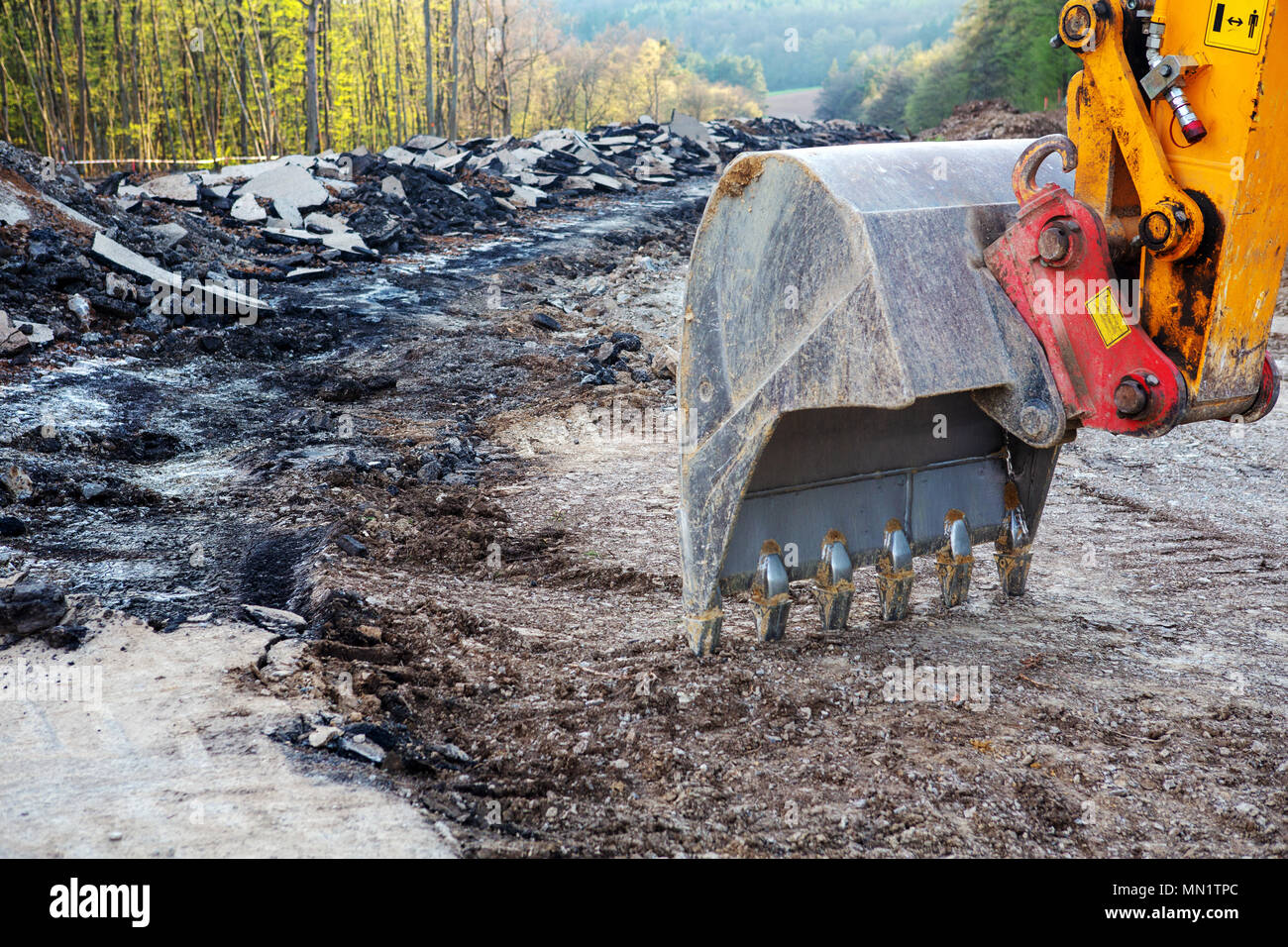 closeup of an excavator shovel digging in dirt at road construction Stock Photo