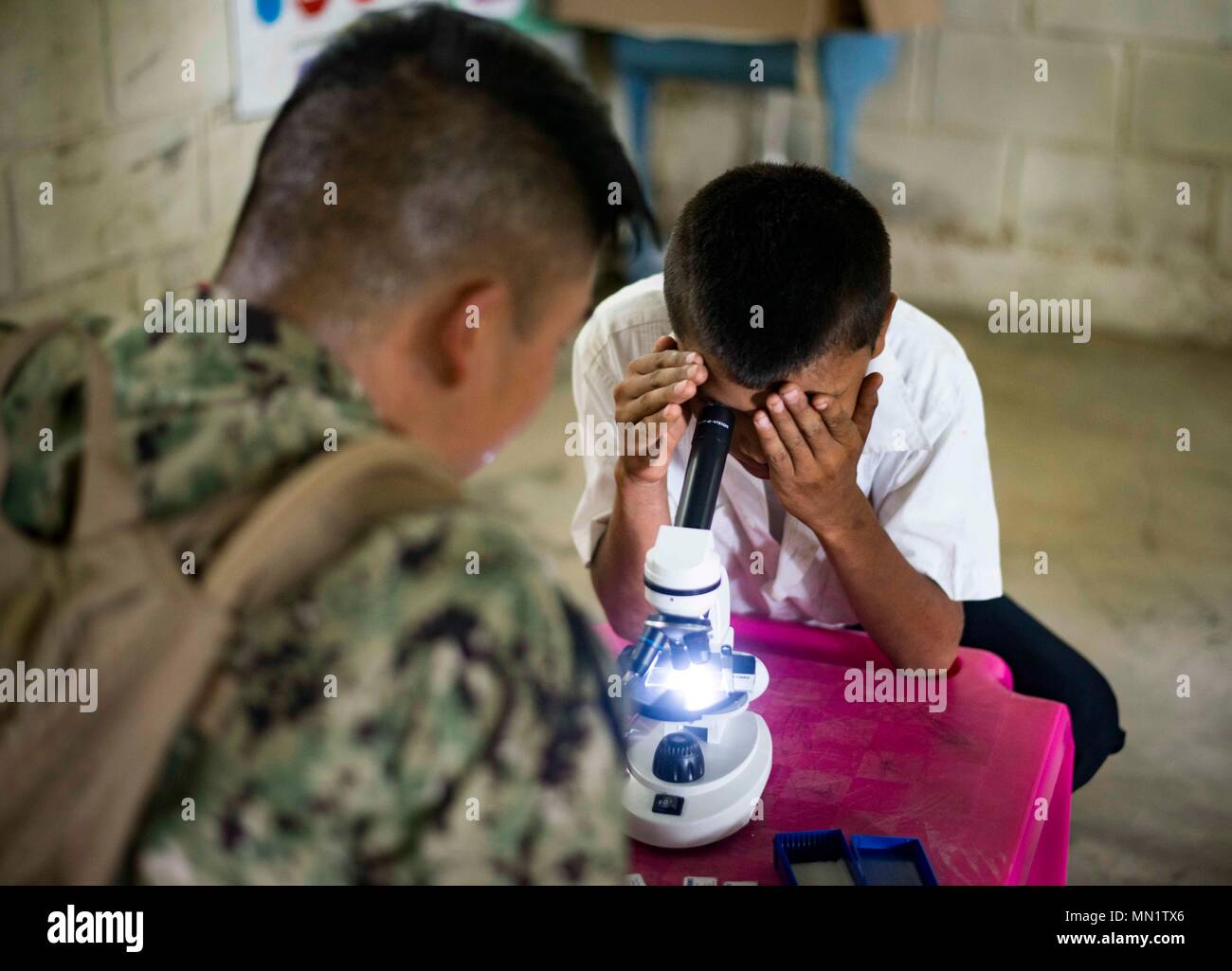 170810-N-KW679-0083 Tarros, Honduras (August 10, 2017) Hospital Corpsman 2nd Class Yang Yang, assigned to Navy Environmental Preventive Medicine Unit 5, helps a Honduran student look through a microscope, during a Southern Partnership Station 17 community relations project (COMREL) at Escuela Rural Mixta Luz y Esperanza, a local elementary school SPS 17 is a U.S. Navy deployment, executed by U.S. Naval Forces Southern Command/U.S. 4th Fleet, focused on subject matter expert exchanges with partner nation militaries and security forces in Central and South America. (U.S. Navy photo by Mass Commu Stock Photo