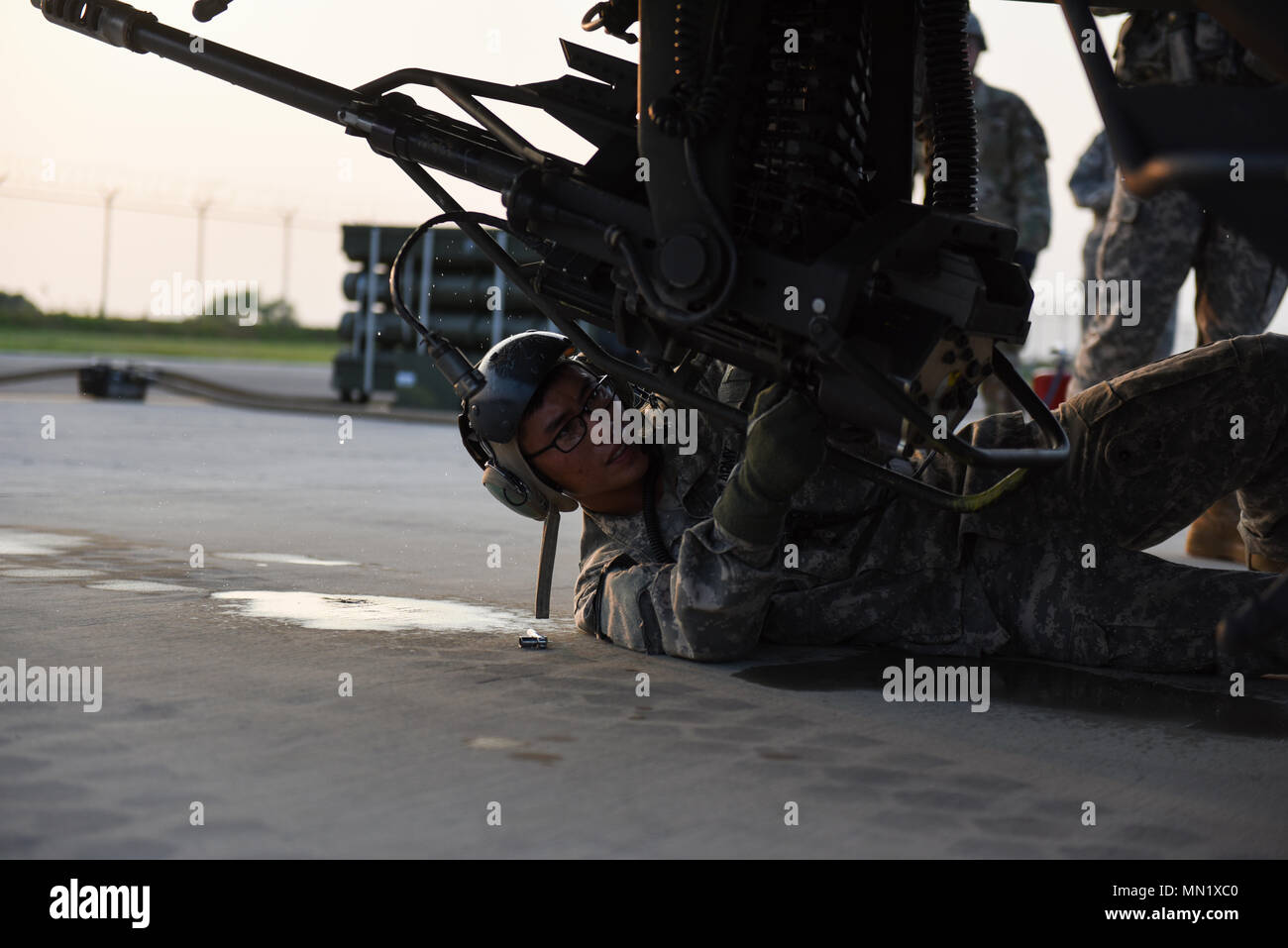 U.S. Army Spc. Kyusuk Jang, an Apache avionics armament specialist from 4-2 ARB, 2CAB, cleans a 30mm machine gun on an AH-64 Apache helicopter at Kunsan Air Base, Republic of Korea, Aug. 7, 2017. The 4-2 Attack Reconnaissance Battalion, 2nd Combat Aviation Brigade, distribution platoon participated in a joint Forward Arming and Refueling Point at Kunsan which allowed the 2CAB to extend its reach beyond what was originally possible for them. (U.S. Air Force photo by Senior Airman Michael Hunsaker/released) Stock Photo