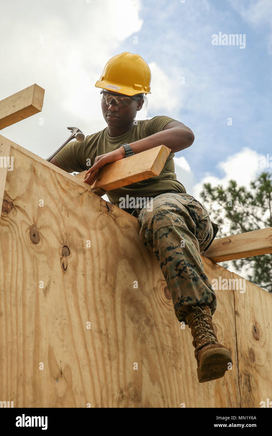 U.S. Marine Corps Cpl. Natasha Williams, Combat Engineer, 8th Engineer Support Battalion, 2nd Marine Logistics Group, hammers a nail into wood at Landing Zone Plover on Camp Lejeune, N.C., Aug. 11, 2017. The structure was built for students at the Marine Corps Engineer School to practice breaching procedures. (U.S. Marine Corps photo by Lance Cpl. Tyler W. Stewart) Stock Photo