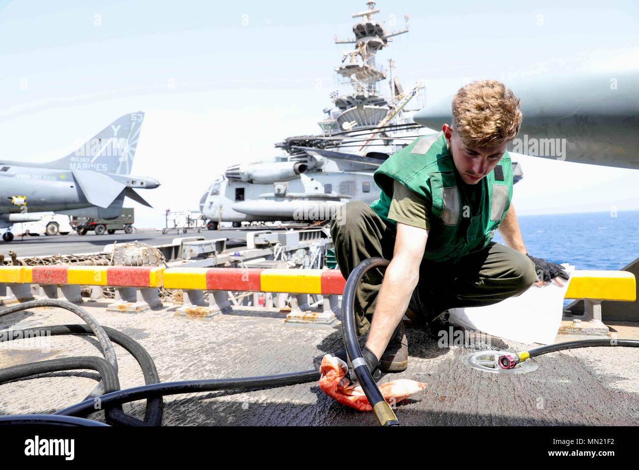 170813-N-UM082-0038 U.S. 5TH FLEET AREA OF OPERATIONS (August 13, 2017) Cpl. Jonathan Lambert, attached to the 24th Marine Expeditionary Unit, cleans excess hydraulic fluid while performing routine maintenance on a AV-8B Harrier on the flight deck of the multipurpose amphibious assault ship USS Bataan (LHD 5). The ship and its ready group are deployed in the U.S. 5th Fleet area of operations in support of maritime security operations to reassure allies and partners, and preserve the freedom of navigation and the free flow of commerce in the region. (U.S. Navy photo by Mass Communication Specia Stock Photo