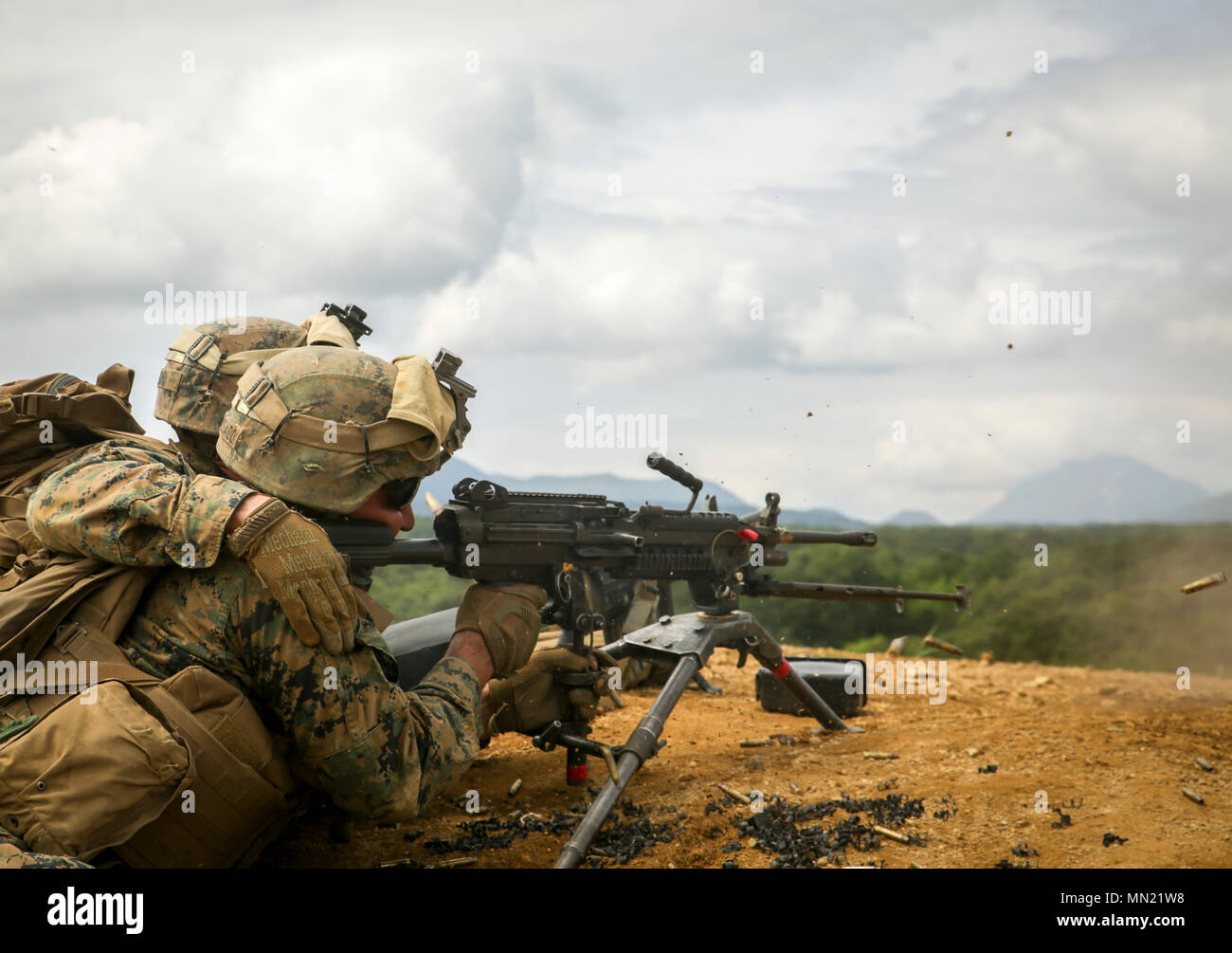 Lance Cpl. Quinn Gurn (left) feeds ammunition into Lance Cpl. Jaziel Lopezrosado's (right) M240B machine gun Aug. 16, 2017 at the live fire range in Hokudaien, Japan, during Northern Viper 17. The service members assaulted the target by cover and maneuver and suppressed fire from Japanese tanks and U.S. light armored vehicles. The U.S. has a vested interest in a secure Pacific; Combined-joint exercises enhance regional cooperation between participating nations to collectively deter security threats. Gurn, a Greenville, South Carolina native, is a team leader and Lopezrosado, an Arecibo, Puerto Stock Photo