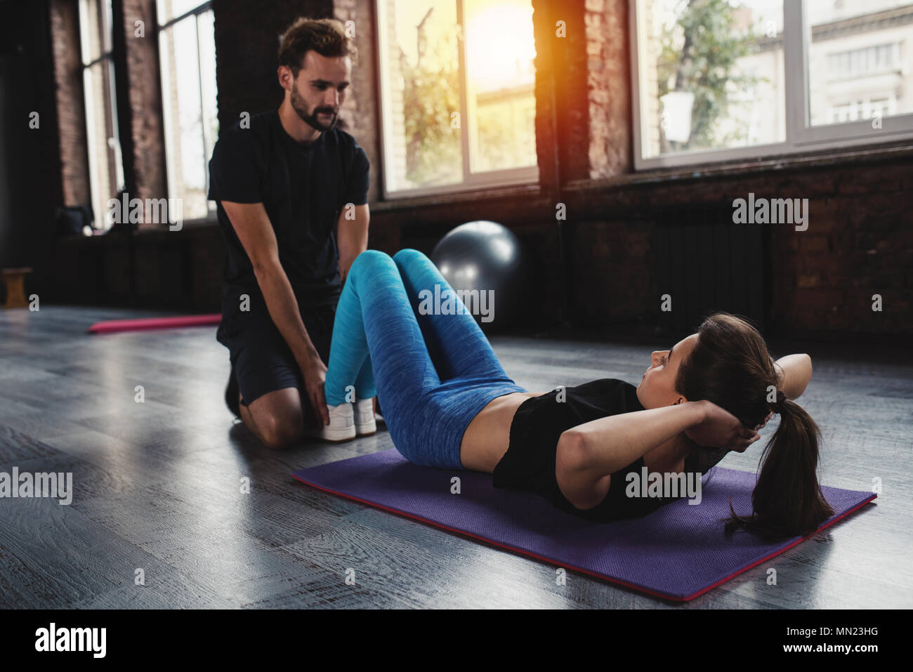 Personal trainer helps a girl with the gym exercises Stock Photo
