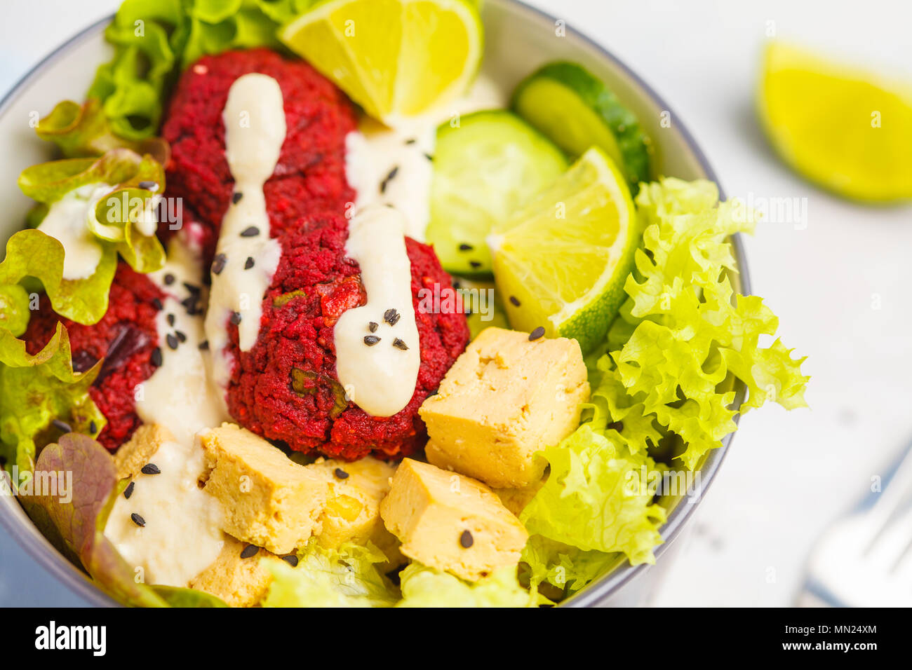 Vegan buddha bowl with beetroot meatballs, vegetables, tahini dressing