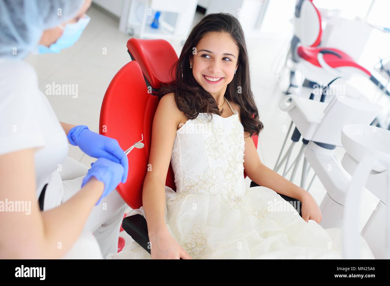 Little cute girl smiling in red dental chair Stock Photo