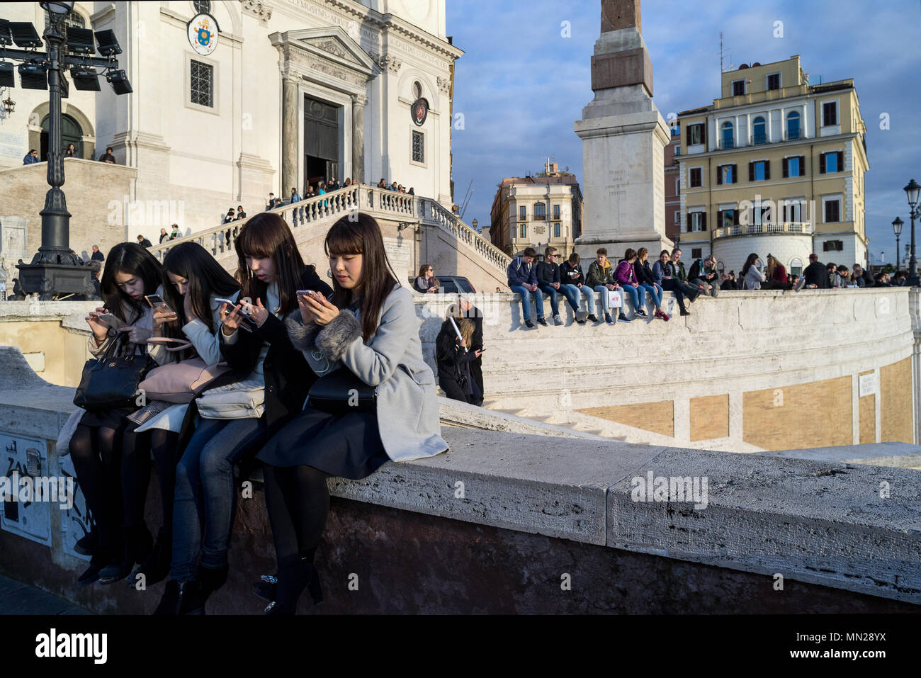 Rome, 'Trinità dei Monti', Italy: Four Japanese girls use their smartphones while sitting on the wall of the 'Trinità dei Monti' staircase in Rome Stock Photo