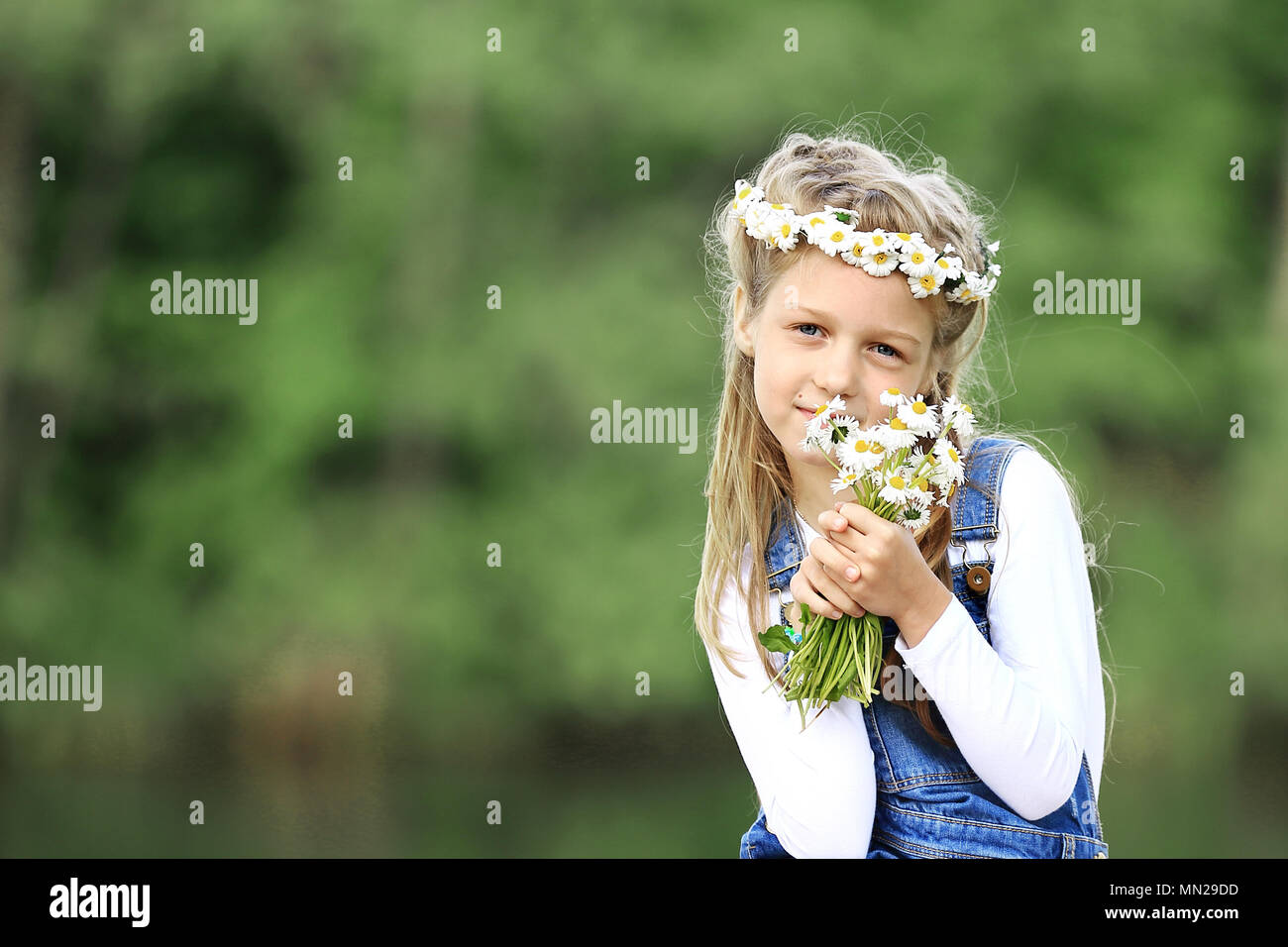 cute little girl in a wreath and a bouquet of wildflowers on a picnic ...