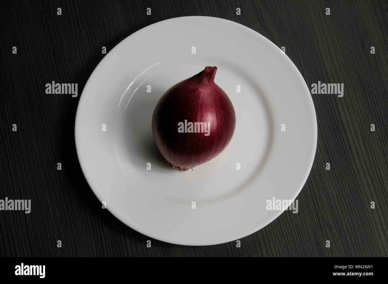 Red onion on the plate on wooden table Stock Photo