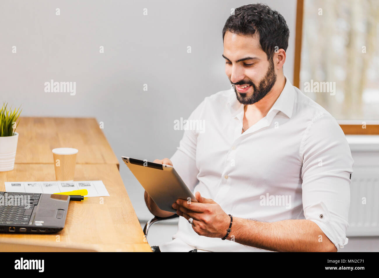 Closeup of man using tablet, touching computer screen while working in cozy office Stock Photo