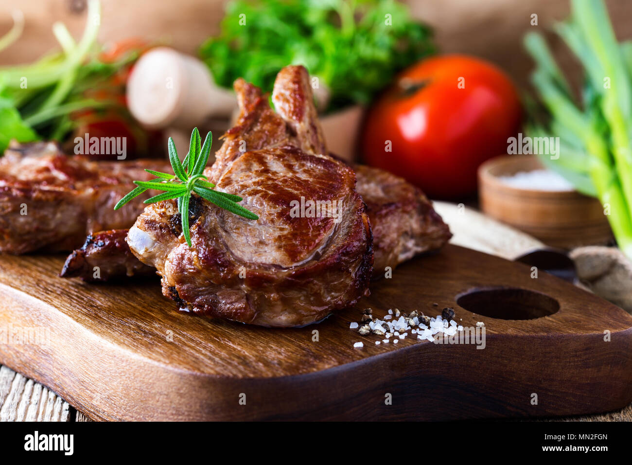 Roasted veal chops with fresh herbs and vegetables on rustic wooden