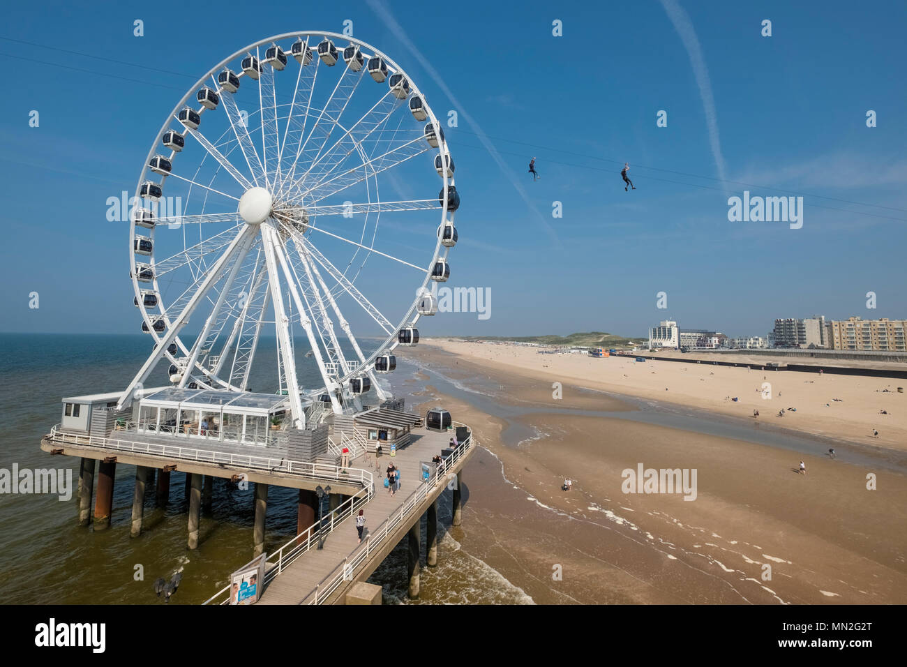 Ferris wheel at Scheveningen pier and beach, with 2 people on zip wire in background, Wassenaar district, The Hague (Den Haag), Netherlands Stock Photo