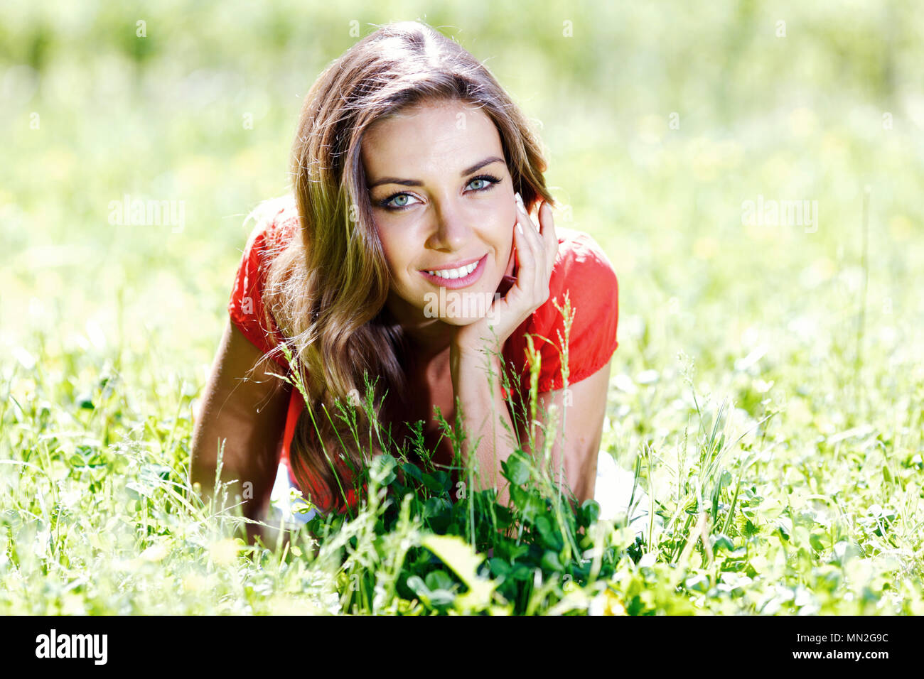 beautiful young woman in red dress lying on grass Stock Photo - Alamy