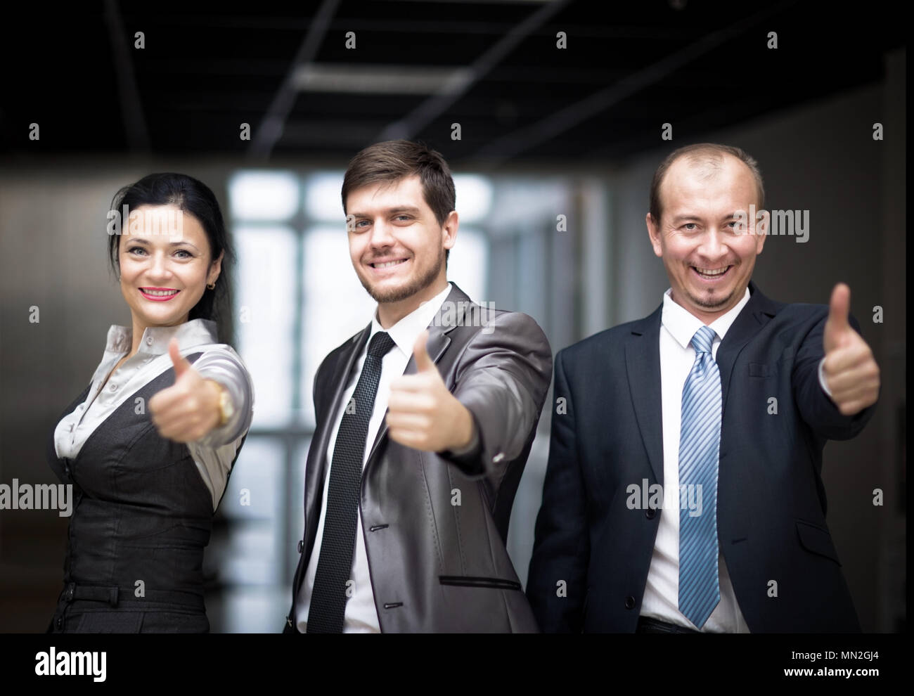 Successful business people with thumbs up and smiling Stock Photo - Alamy