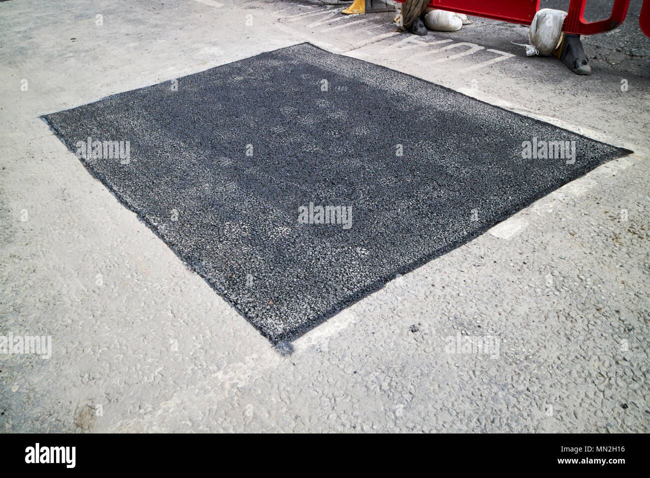 freshly laid section of tarmac to repair series of potholes in the road England UK Stock Photo