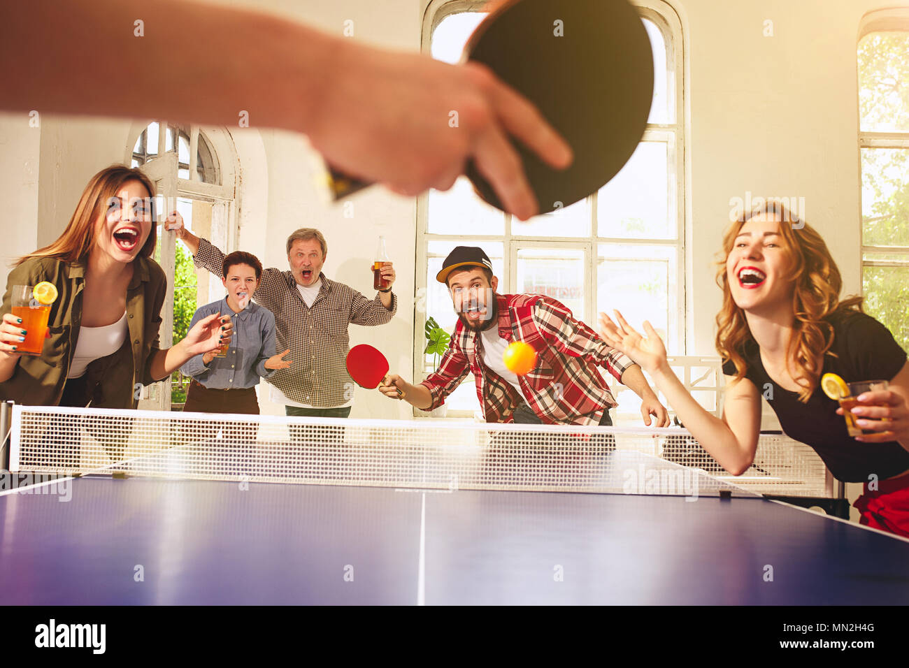 Group of happy young friends playing ping pong table tennis Stock Photo