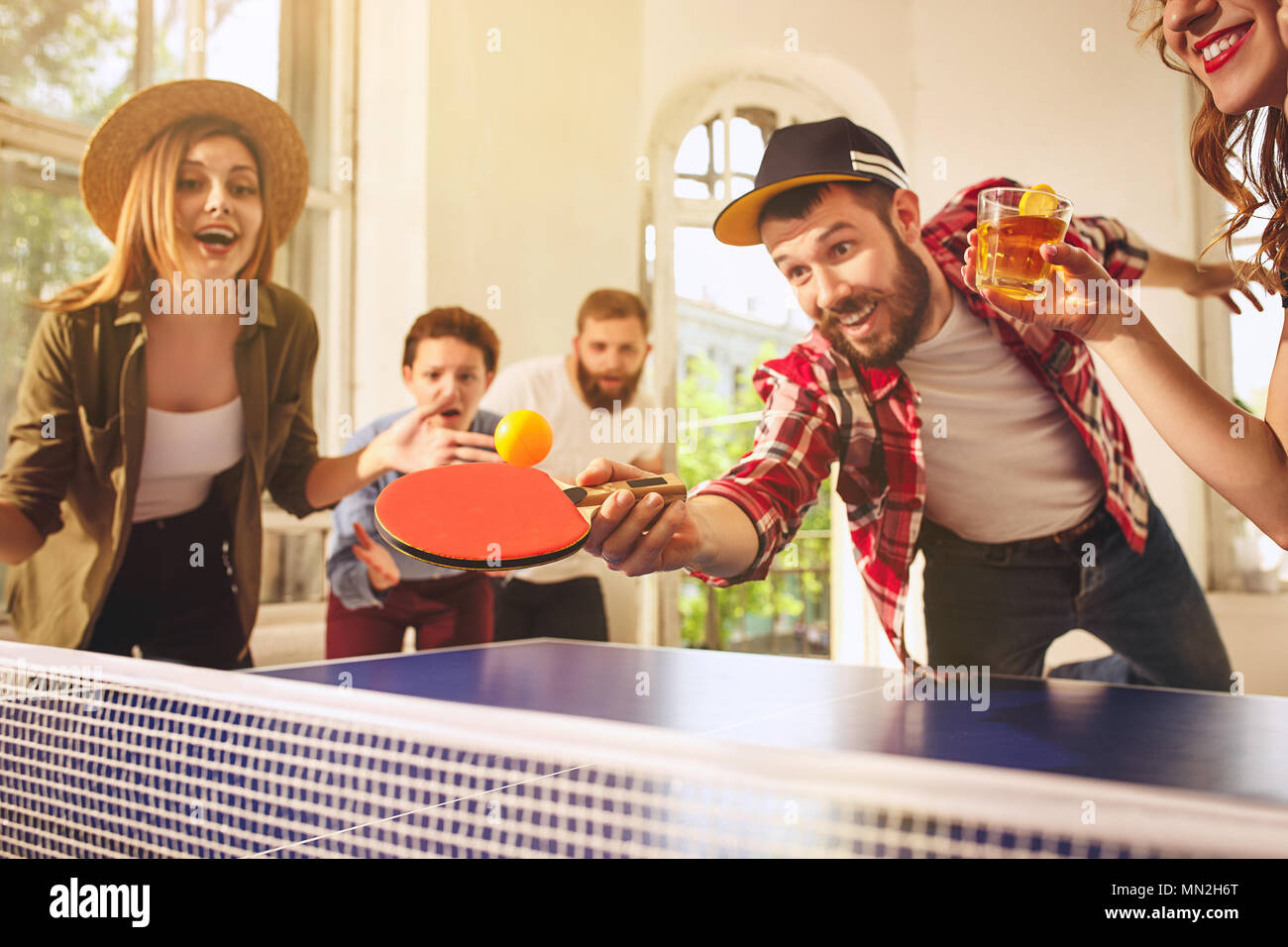 Group of happy young friends playing ping pong table tennis Stock Photo