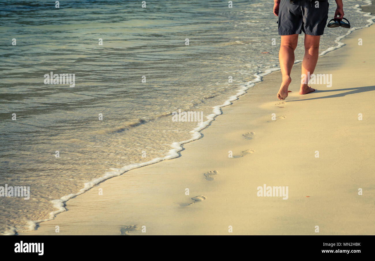 A person walkng along a sand beach on an island in BVI Stock Photo