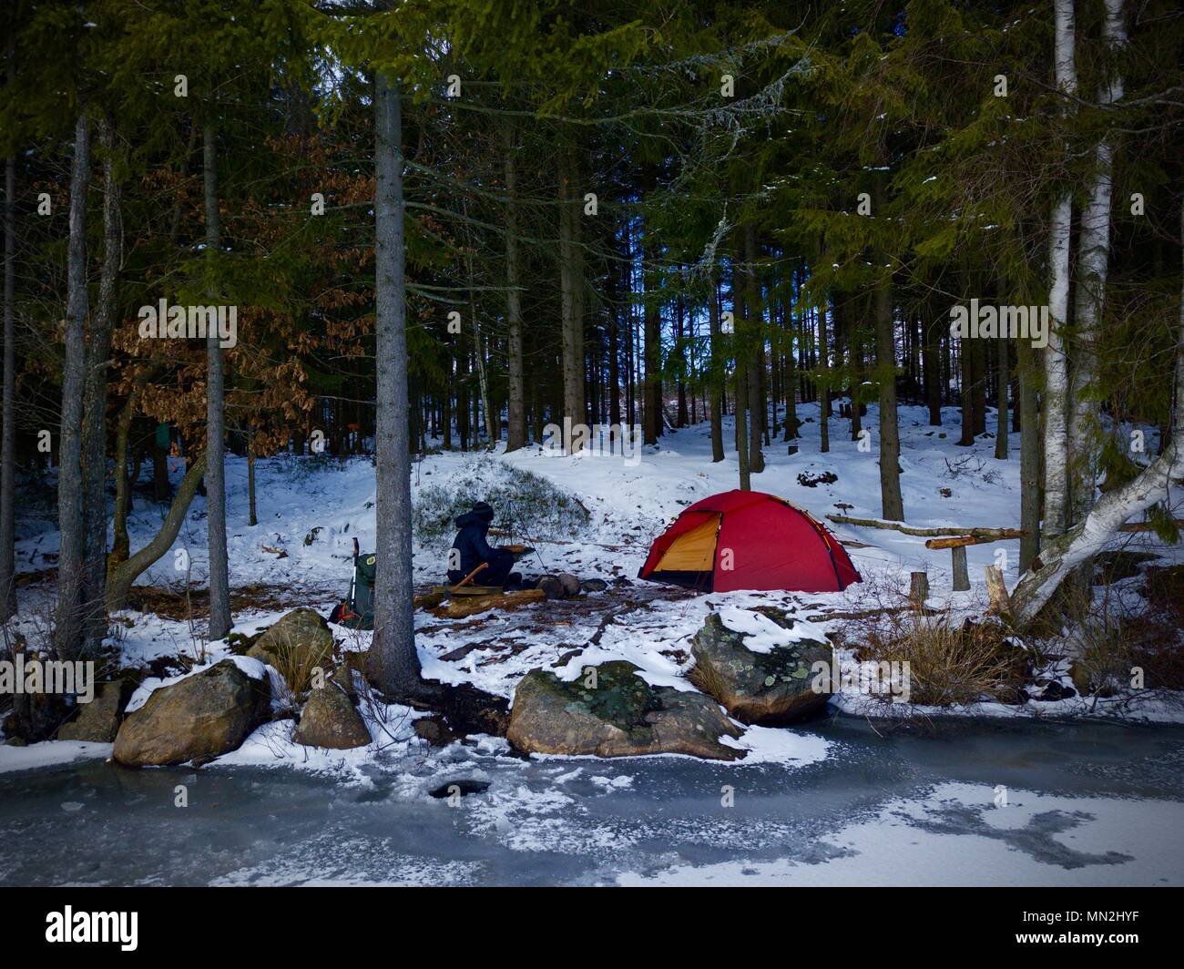 Wild forest winter camp with tent in front of frozen lake in Sweden. Stock Photo