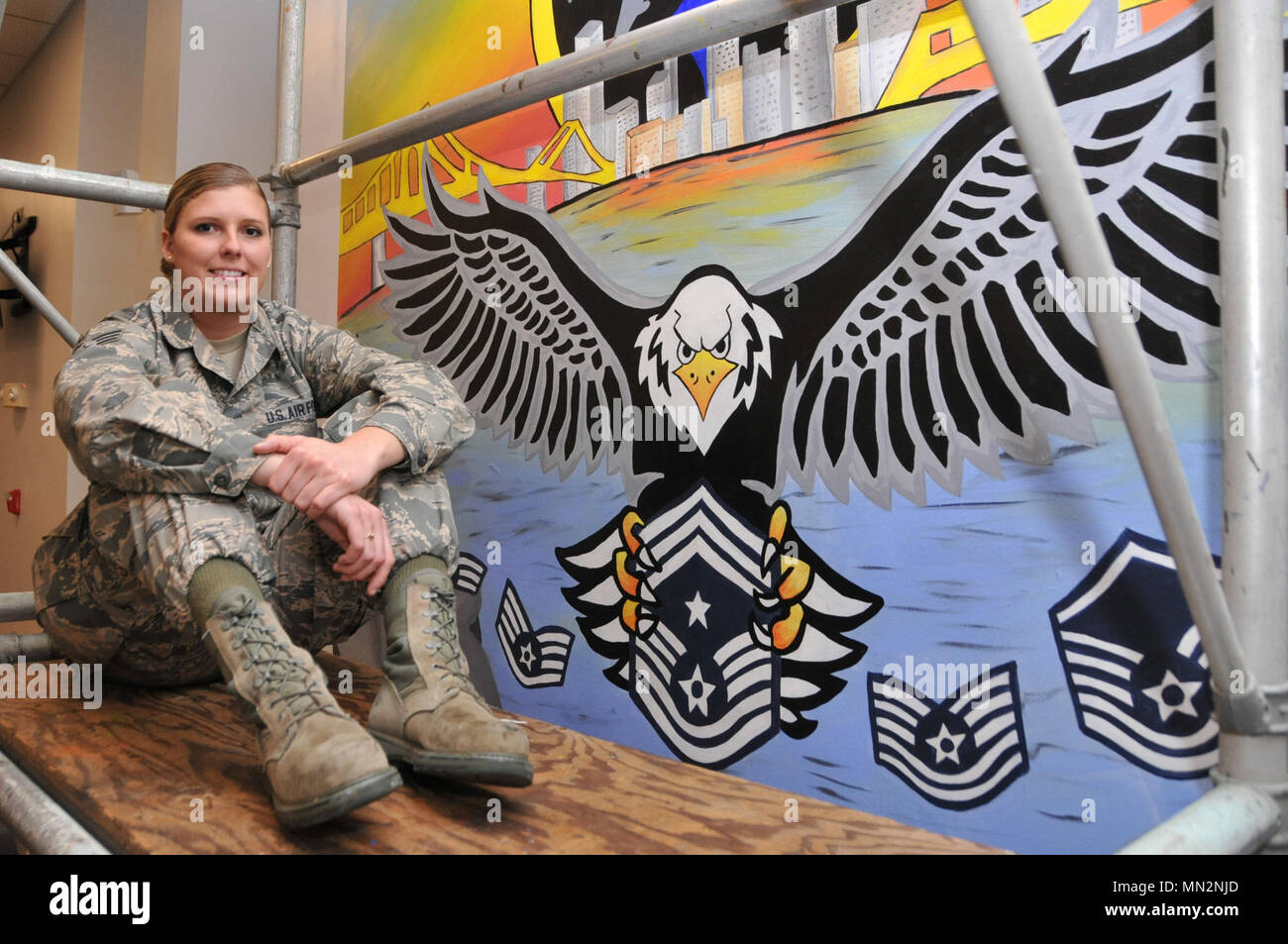 Senior Airman Kayla R. Stapf, a member of the 171st Air Refueling Wing Force Support Squadron, poses beside the mural that she both designed and painted in the dining facility at the 171st Air Refueling Wing, Pittsburgh Pennsylvania, Aug. 11, 2017. (U.S. Air National Guard photo by Staff Sgt. Ryan A. Conley) Stock Photo