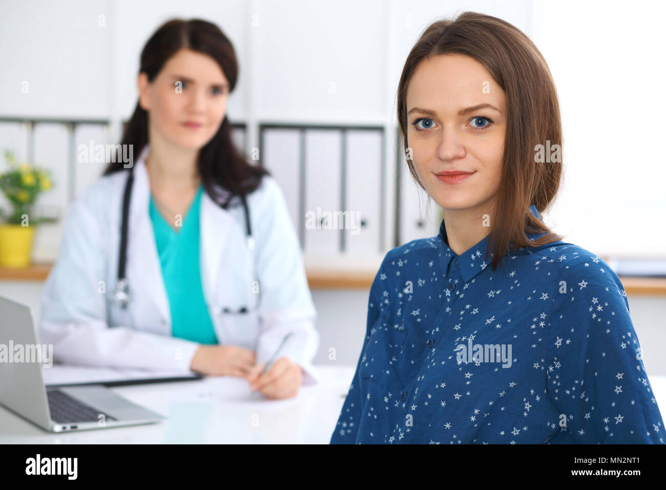 Doctor and patient having a talk while sitting at the desk. Focus on ...