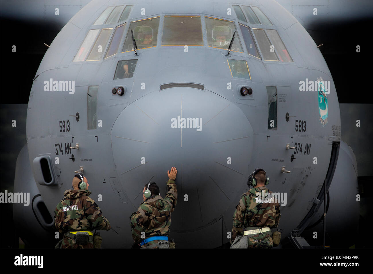 Crew chiefs from the 374th Aircraft Maintenance Squadron await a C-130J Super Hercules engine to start during Exercise Beverly Morning 17-05 at Yokota Air Base, Japan, Aug. 18, 2017. The training is designed to test the ability of Airmen to survive in austere environments with chemical, biological, radiological, nuclear and explosive hazards. (U.S. Air Force photo by Yasuo Osakabe) Stock Photo