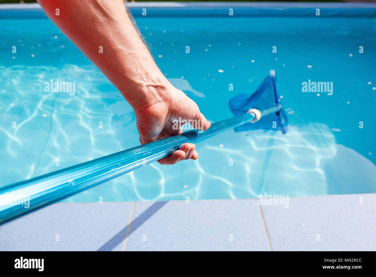 Worker make maintenance of swimming pool. Male hand hold pool net