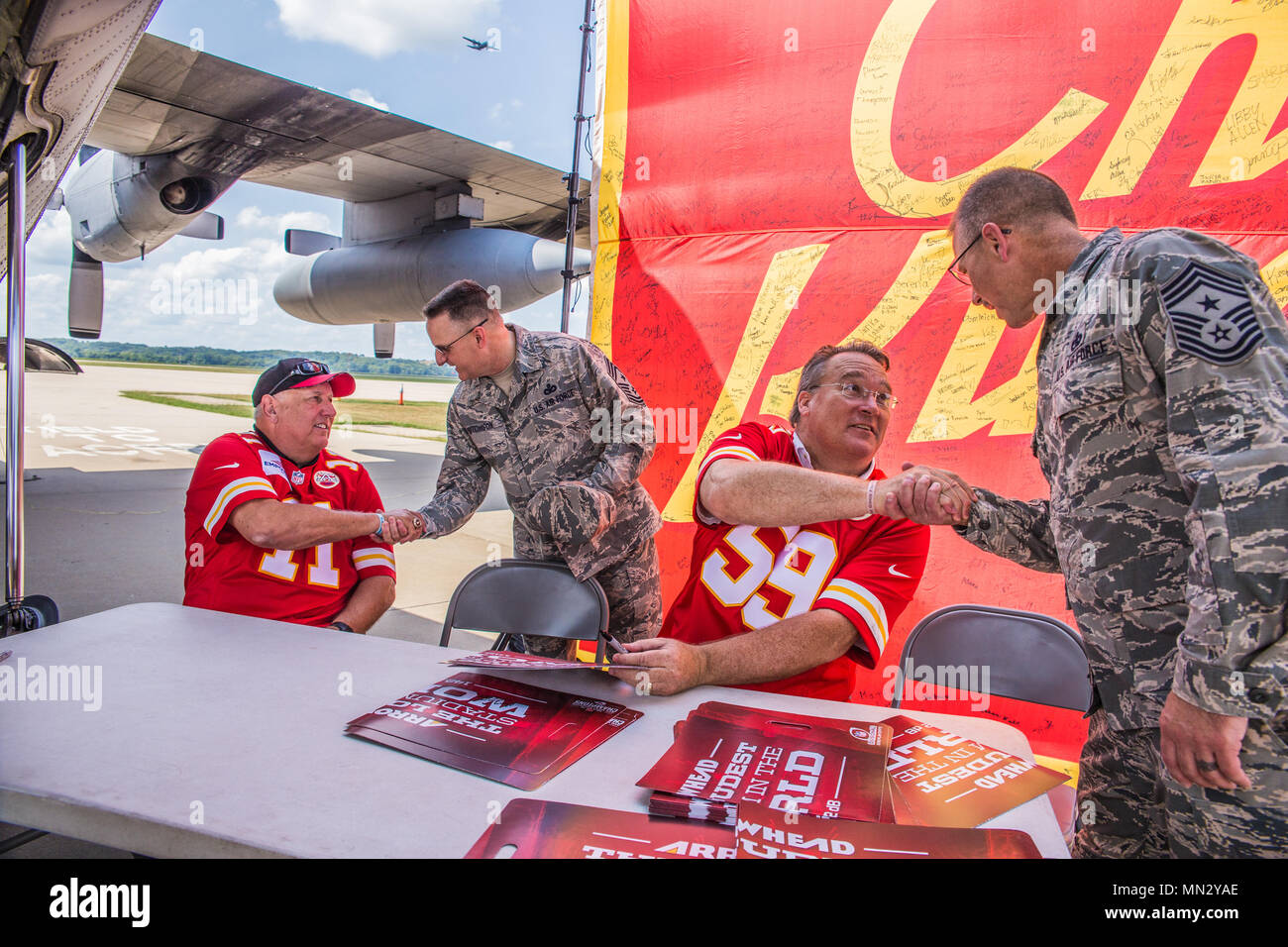 Tony Adams, retired Kansas City Chiefs NFL player (left) shakes hands with Chief Master Sgt. Harold Hutchinson, command chief master sergeant of North American Aerospace Defense Command and U.S. Northern Command, and Gary Spani, retired KC Chiefs player (second from right) shakes hands with Chief Master Sgt. Randy Miller, command chief master sergeant of the 139th Airlift Wing, Missouri Air National Guard, during a visit to Rosecrans Air National Guard Base in St. Joseph, Mo., August 15, 2017. The visit was part of a McDonald’s Restaurant Heart of America Co-Op 15-stop tour for local charities Stock Photo