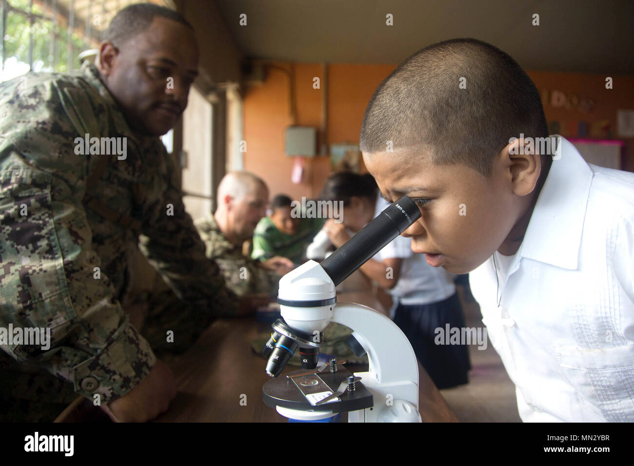 170823-A-QE286-0029 AGUAN, Honduras (August 23, 2017) U.S. Navy Hospital Corpsman 1st Class Dominic Ladmirault, assigned to Navy Entomology Center of Excellence, helps a boy examine an insect through a microscope at Escuela Lidia Handal, during a Southern Partnership Station 17 community relations project (COMREL). SPS 17 is a U.S. Navy deployment executed by U.S. Naval Forces Southern Command/U.S. 4th Fleet, focused on subject matter expert exchanges with partner nation militaries and security forces in Central and South America. (U.S. Army photo by SPC Judge Jones/Released) Stock Photo