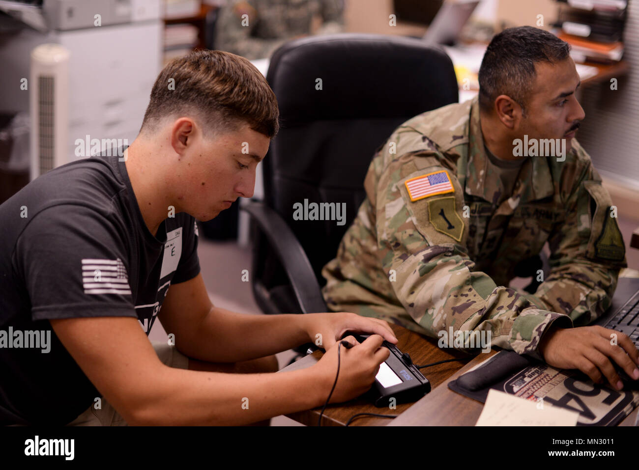 Raleigh, North Carolina - Nathan Jones, works with Sgt. 1st Class Carlos Rojas, a guidance counselor for the NCNG’s Recruiting and Retention Battalion, to sign and complete his enlistment contract at the Military Entrance Processing Station in Raleigh, August 11, 2017. When in the 4th grade, Jones, who the son of Chief Warrant Officer 3 Bruce Jones, the NCNG Force Integration Readiness Officer, told the NC Adjutant General, who at the time was Maj. Gen. William E. Ingram Jr., that he would join the NCNG when he grew up, just like his dad. (U.S. Army Photo by Staff Sgt. Mary Junell) Stock Photo