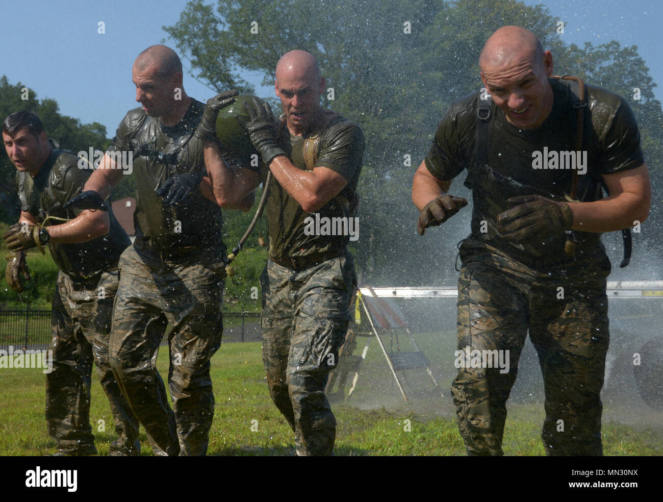 From left) Staff Sgt. Diego Solano, Senior Master Sgt. James Reynolds,  Tech. Sgt. Dedrick Baublitz, and Staff Sgt. Aaron Jerolmon get sprayed with  a fire hose as a part of an obstacle
